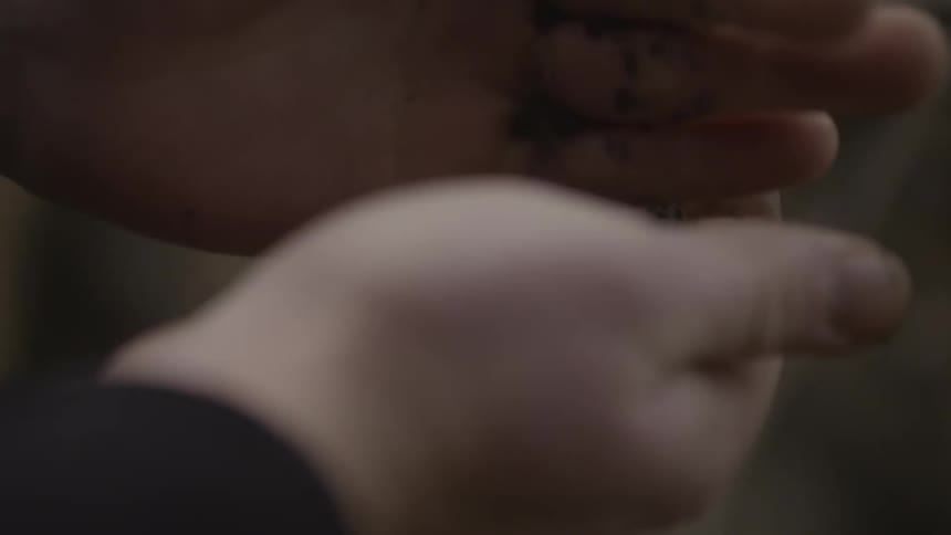 A person rubs dirt between their fingers
