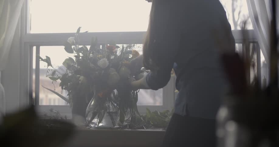 A woman arranges flowers in a vase