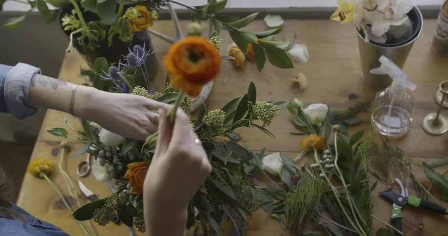 A woman arranges flowers in a vase
