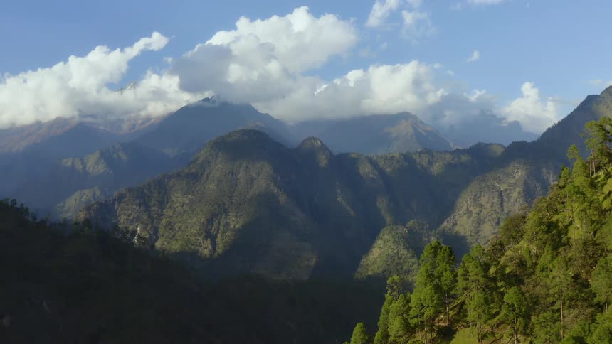 Aerial view of high mountains with clouds in the blue sky
