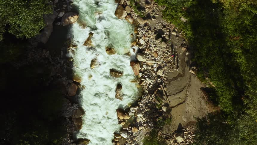 Aerial view of four people walking along a river bank