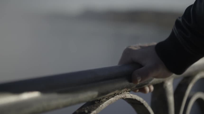 A man's hand grasps a metal railing