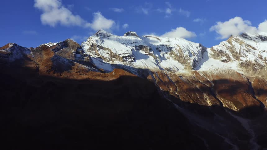 A snow covered mountain range with the sky and clouds in the background