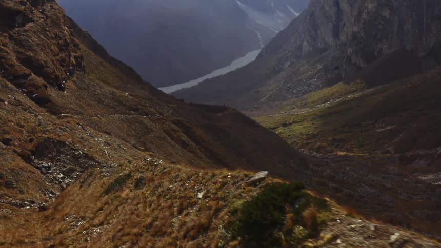 Ridge runs along top of mountain valley leading to snow bordering fog covered mountain
