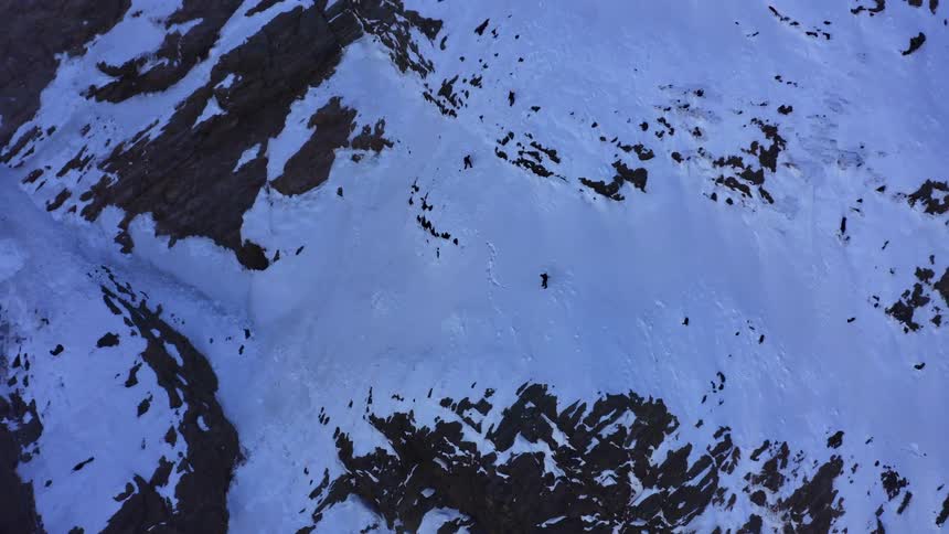A hiker climbing a snowy mountainside alone in winter