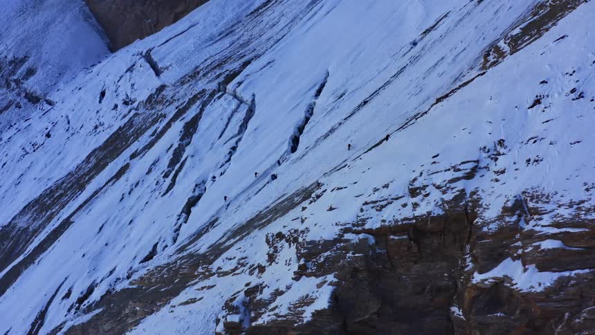People climbing a snow covered mountain range