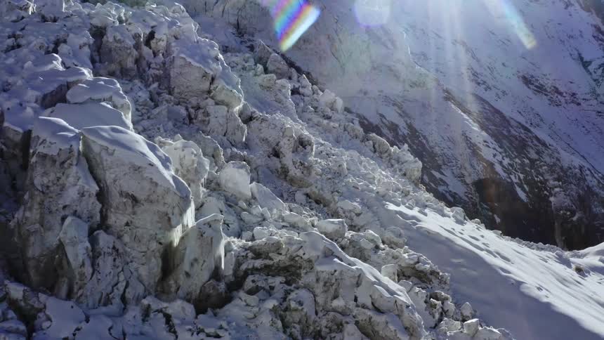 Bright sunlight shines down on a snow covered mountain