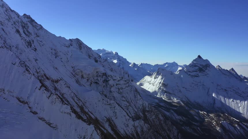 Aerial view of snowy mountain ranges against the cloudless blue sky