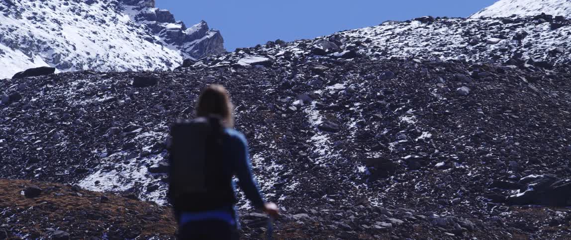 A woman hiking looks up at a mountain
