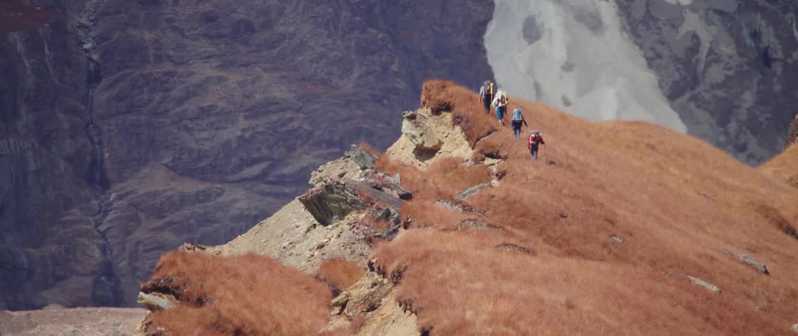 A group of people hiking up a trail on a hill