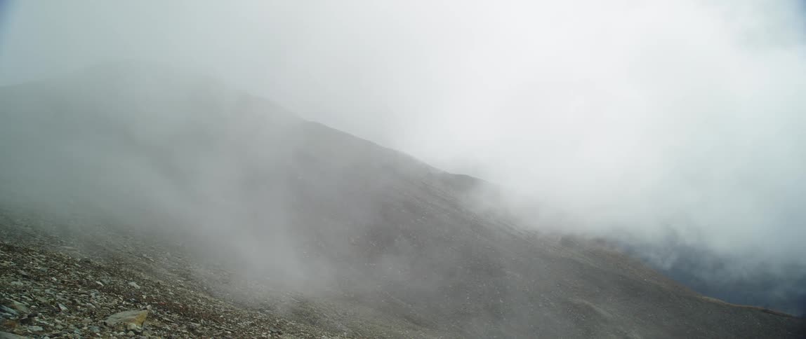 A foggy mountain slope covered in gravel during the day