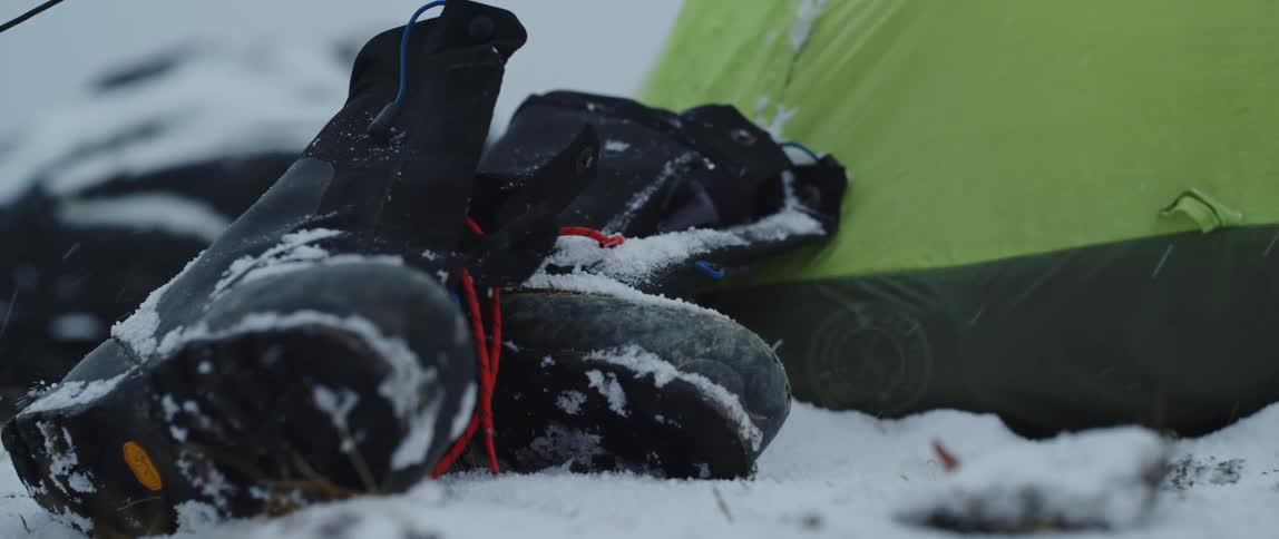 A pair of boots are getting snowed on outdoors
