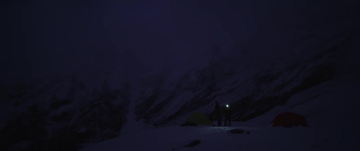 Two people standing outside near tents in the snow
