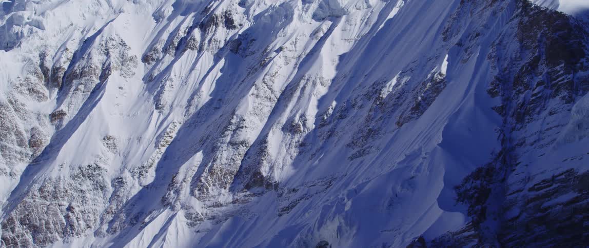 Shadows recede from across a snowy mountain slope during the day