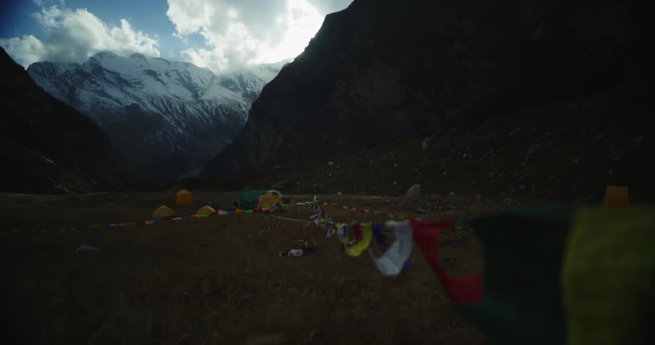 Flags and tents at the base of a mountain