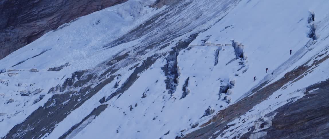 Three people climbing snow covered mountain