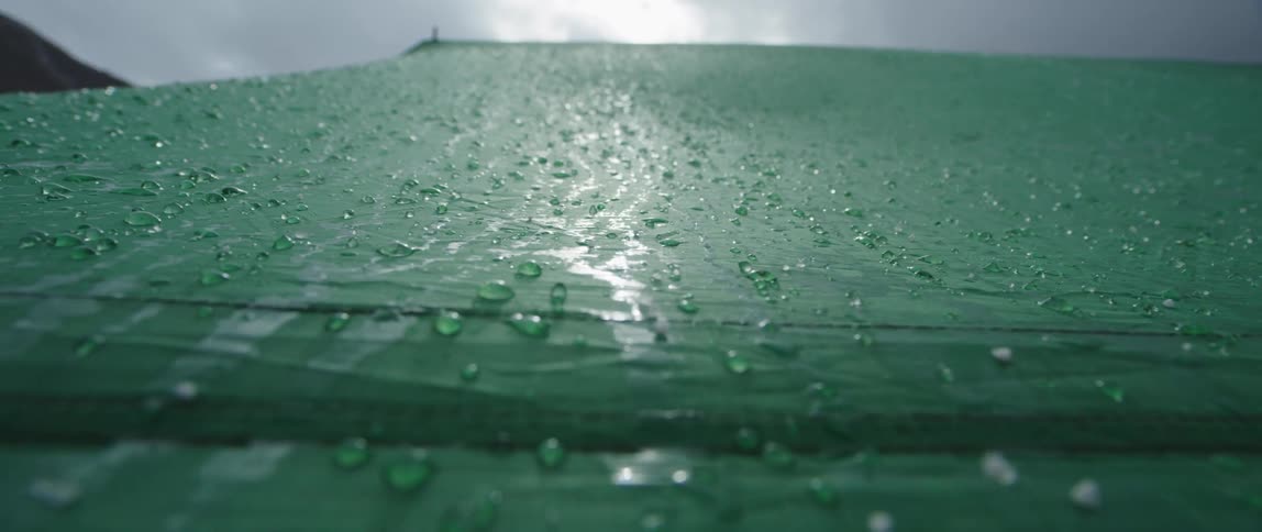 A ground level view of a wet waterproof tent looking upward on a cloudy and rainy day