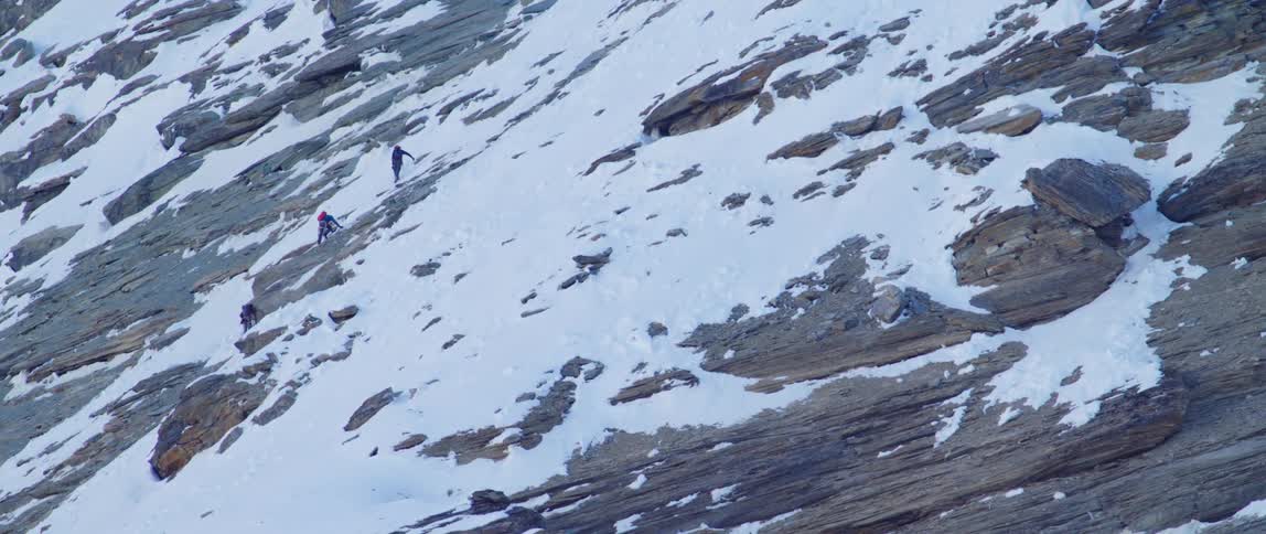 Two people are climbing up a mountain in winter