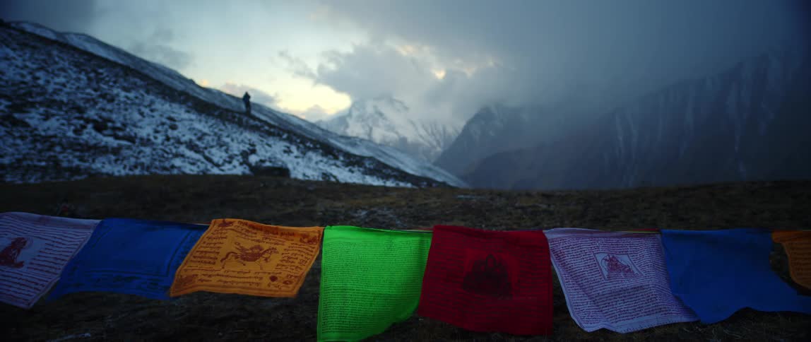 Colorful banners with drawings flap in windwhile snowy slope and fog covered mountains fill background