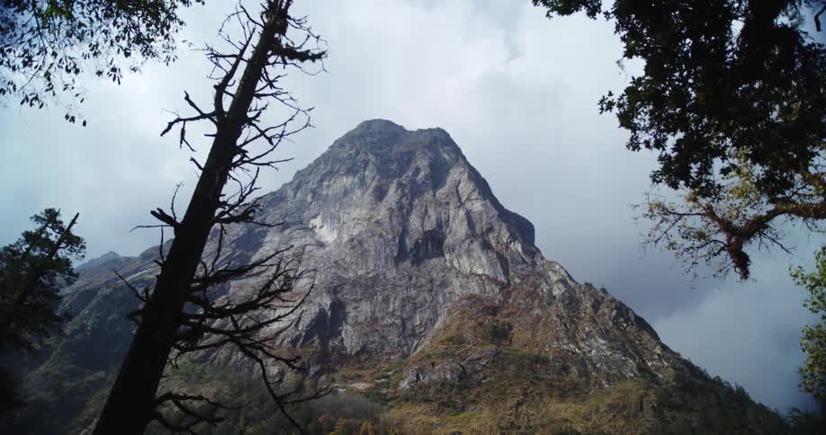 Tall rocky mountain peak against cloudy sky