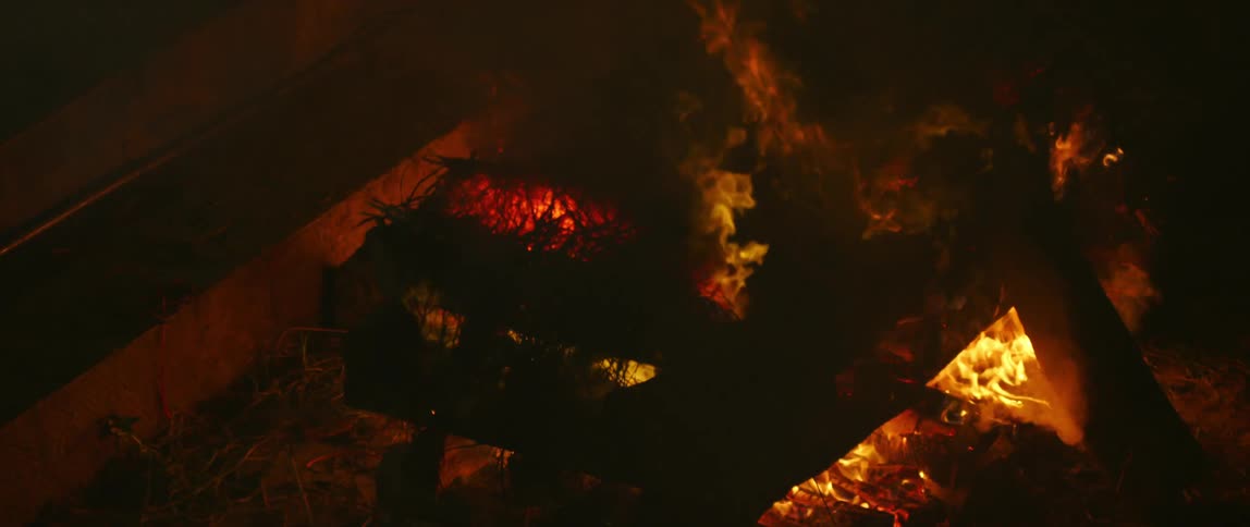 A fire is burning outdoors at night