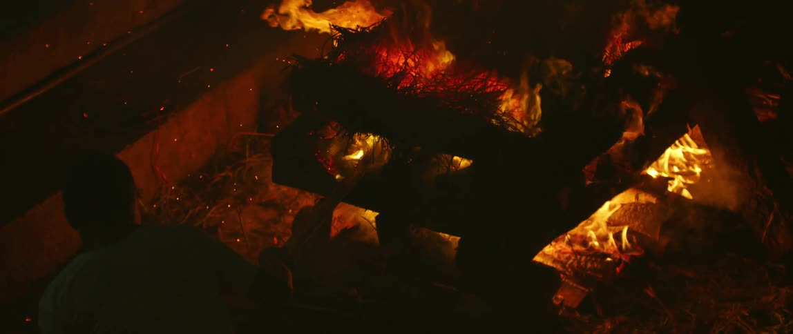 A man pokes at a burning fire with a stick