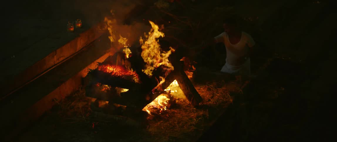 A person with a wristwatch poking a flame with smoke with a stick
