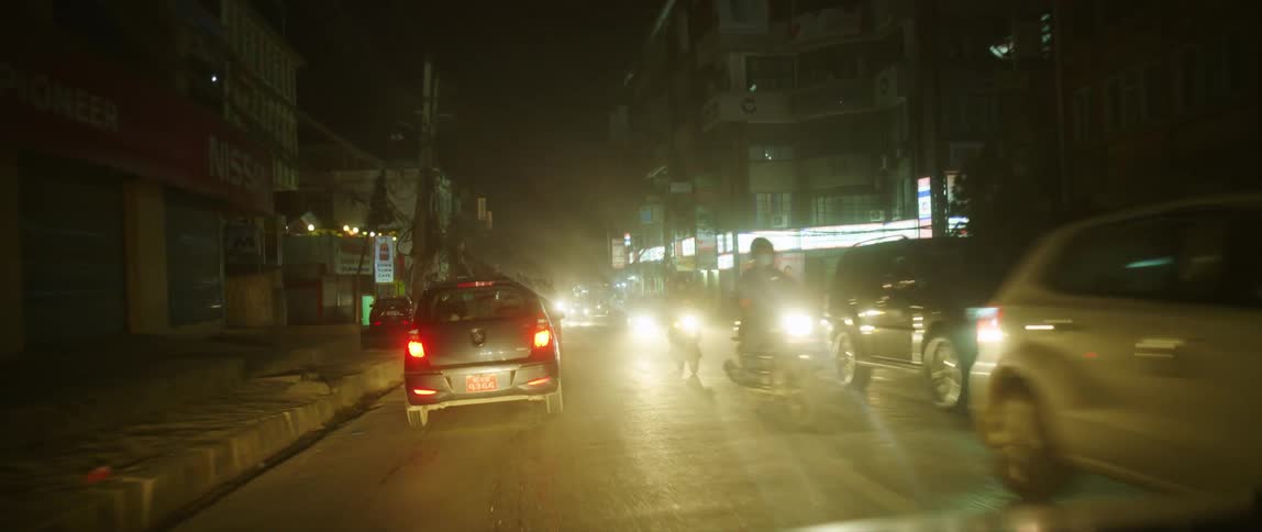 Vehicles and motorcycles pass each other on a city road at night
