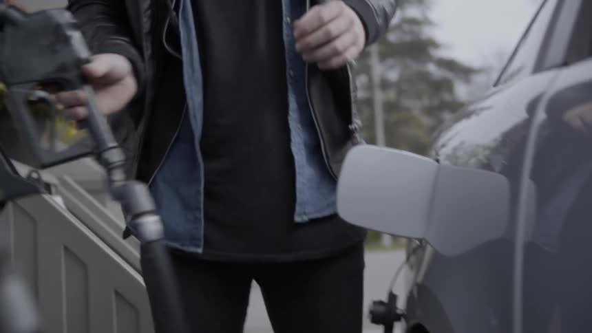 A man walks over to a car and begins to fill it with gas