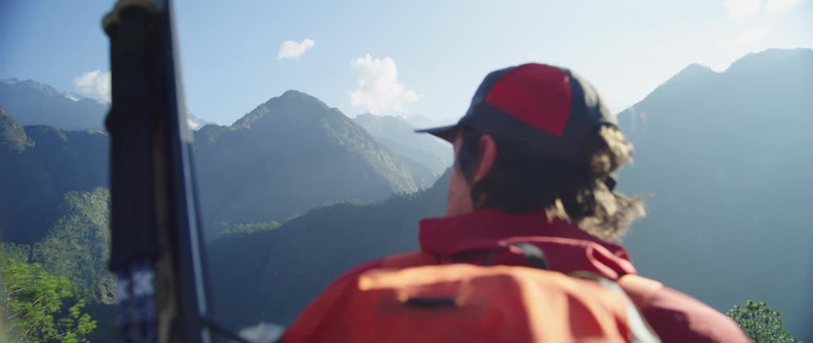 A man stands and looks out at the mountains