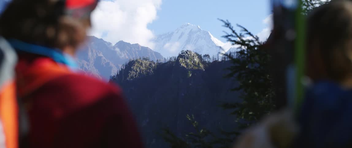 People look across mountains towards tall snow covered peak