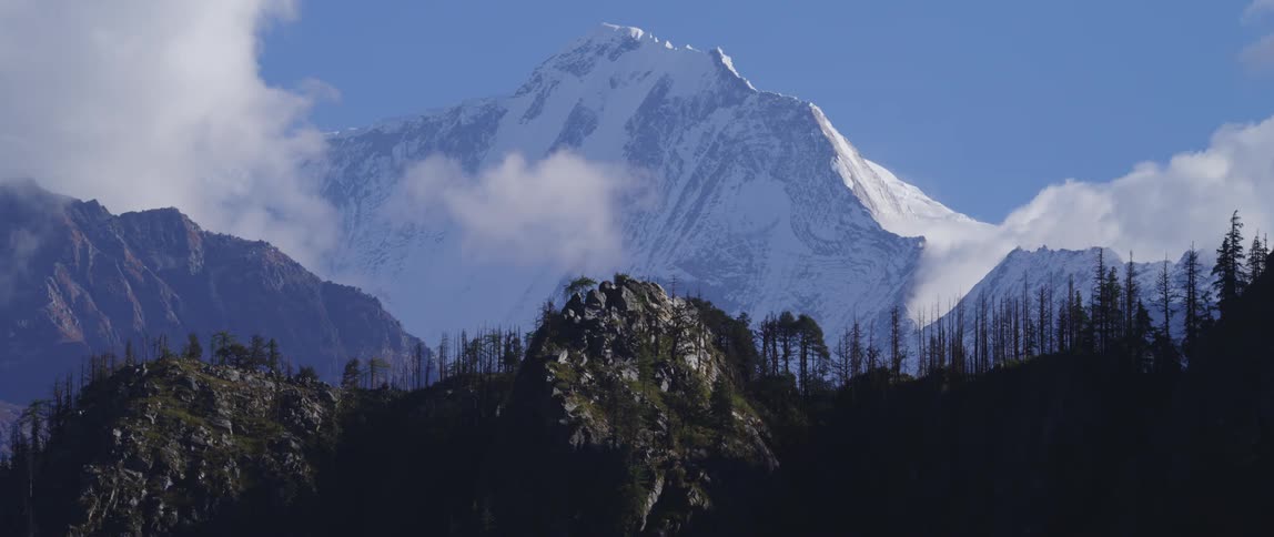 Clouds floating above a snowy mountain range and forest on a winter day