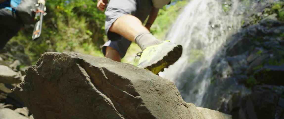 Three people hiking in a forest near waterfalls