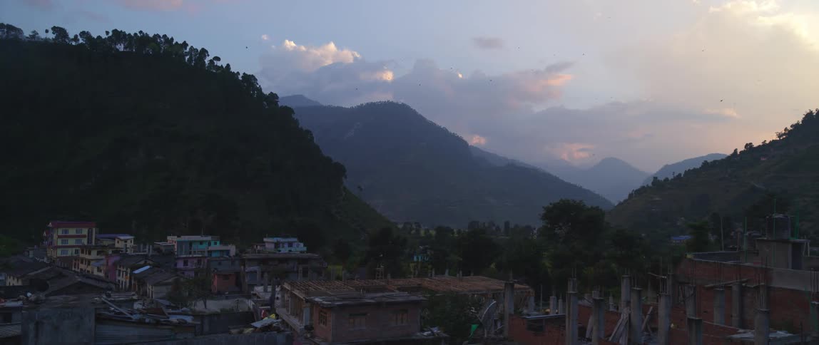 Buildings with chimneys and tall smoke stacks in the valley between tree covered hills