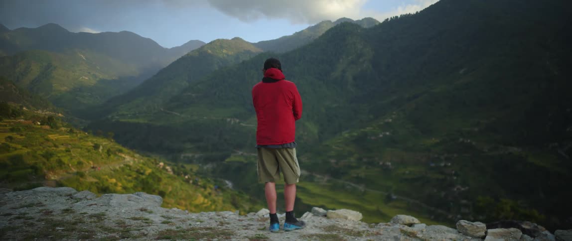 A man is standing by a cliff on the mountain
