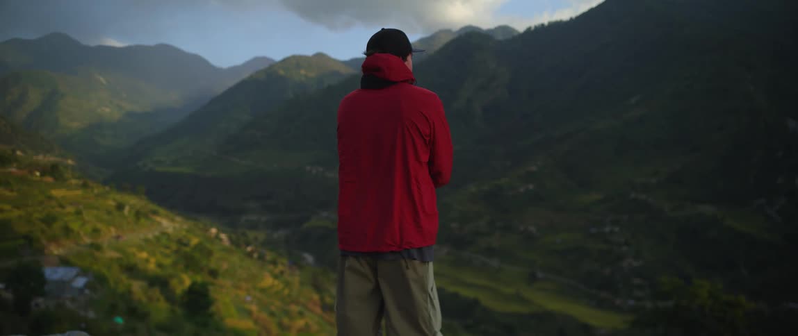 A man stands with his arms crossed on the slope of a canyon