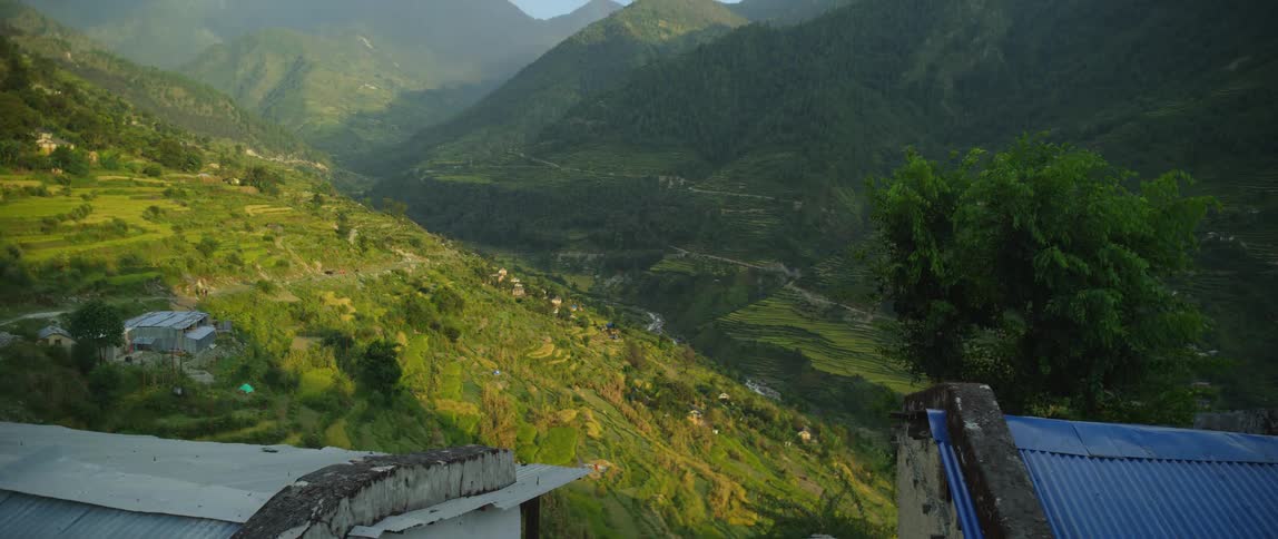 A verdant mountain valley covered in fog on a bright day