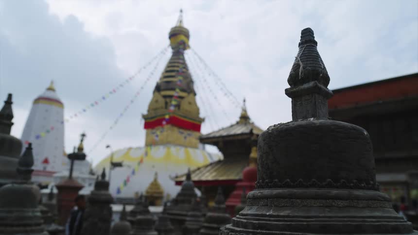 People walk around an asian city and look at columns with detailed carvings