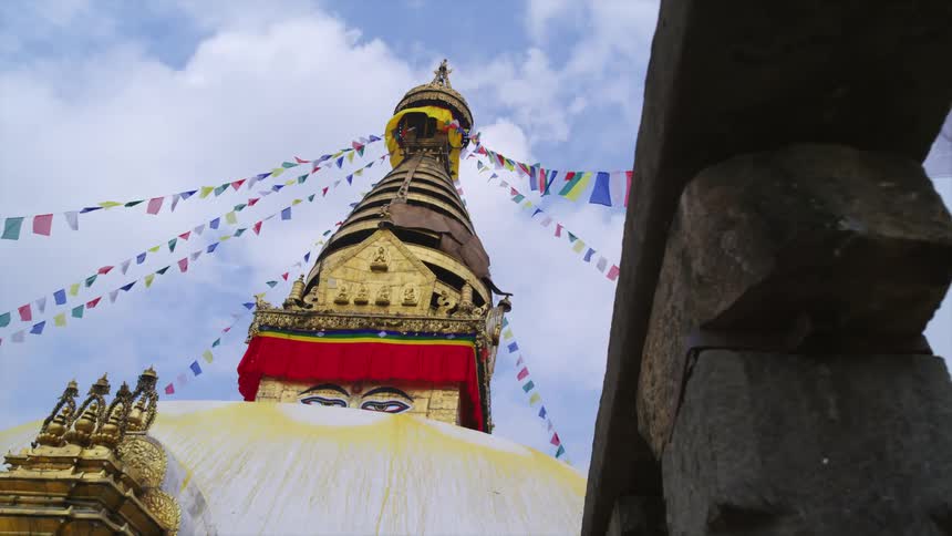 A building with flags and statues with the sky and clouds above