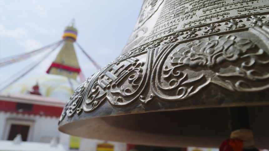A elaborately engraved ceremonial bell outside of a building on a sunny day