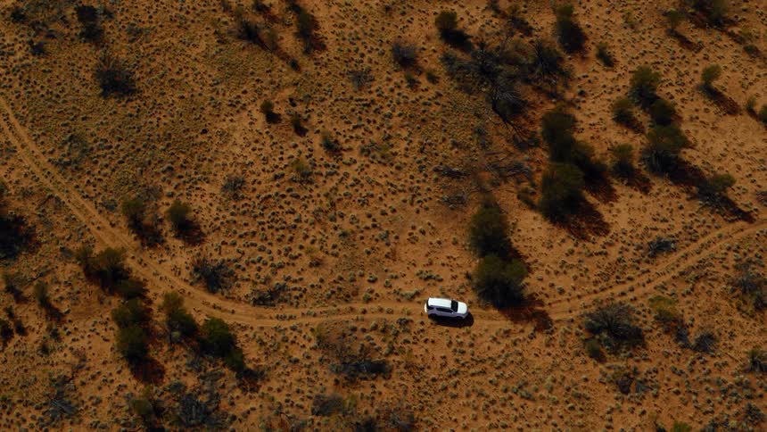 A car is driving in a desert area