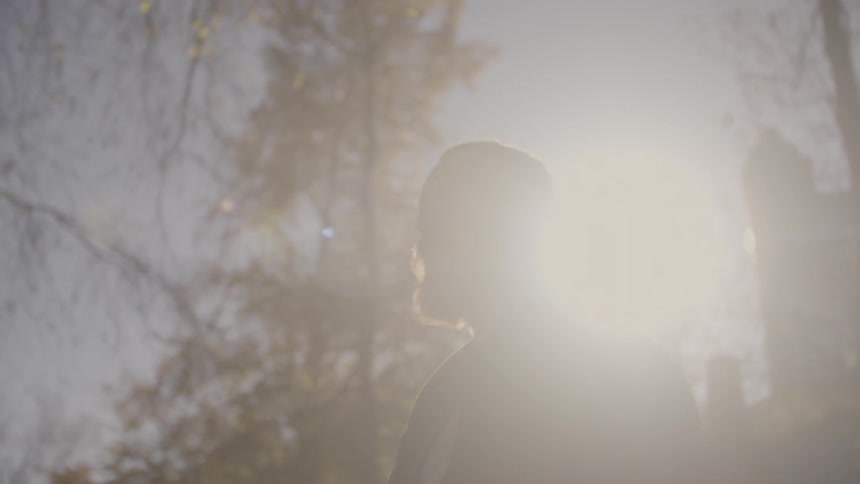 A man is walking on a sunny day by some trees