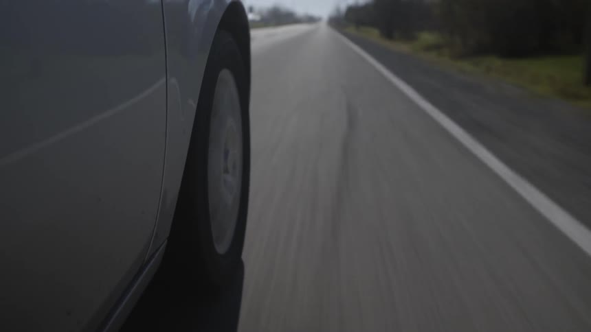 Side view of a car traveling down a country road