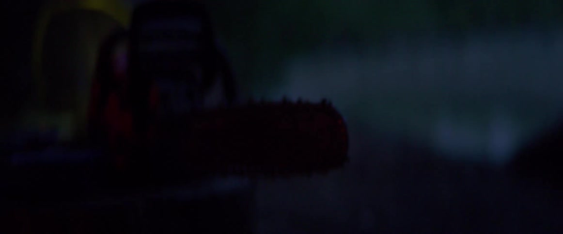 A chainsaw with trees and the sky in the background