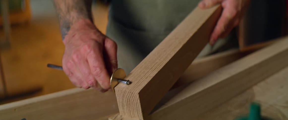 A woodworker using a tool on a piece of wood in a workshop