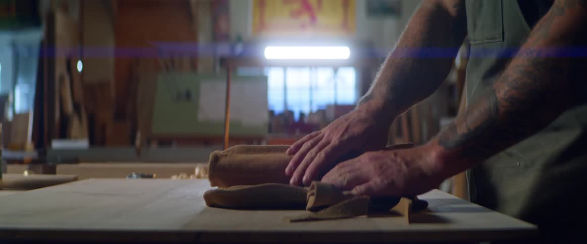 A man unrolls a tool belt in a workshop
