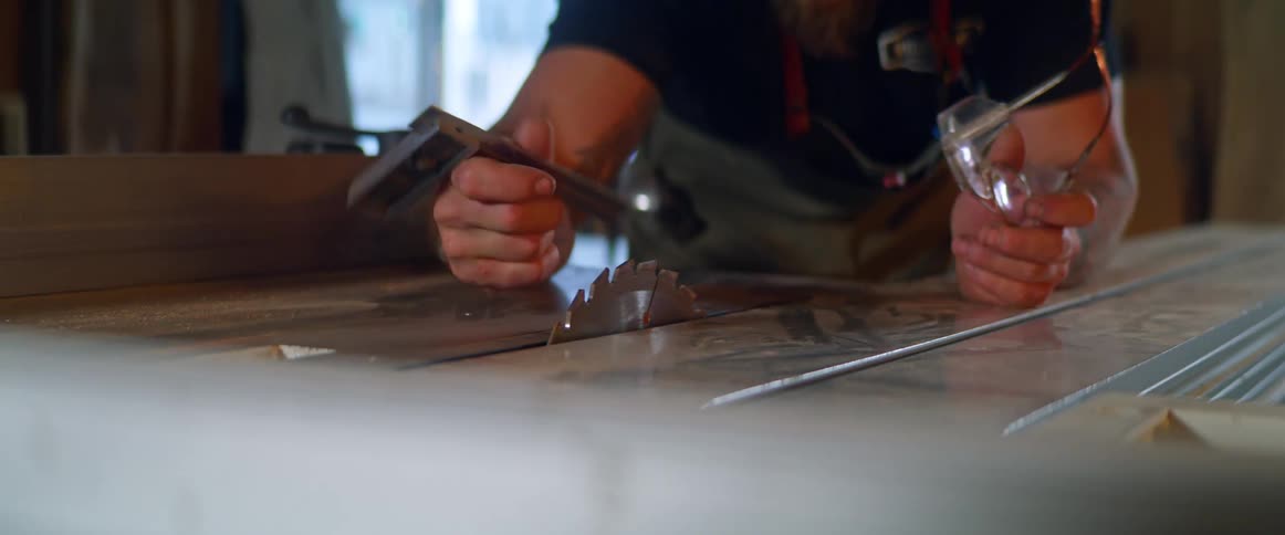 A man uses a small corner square style ruler to measure the height of a saw blade