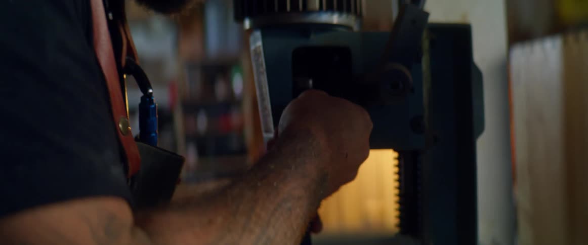 A man adjusts the internal parts of a drill press in a workshop