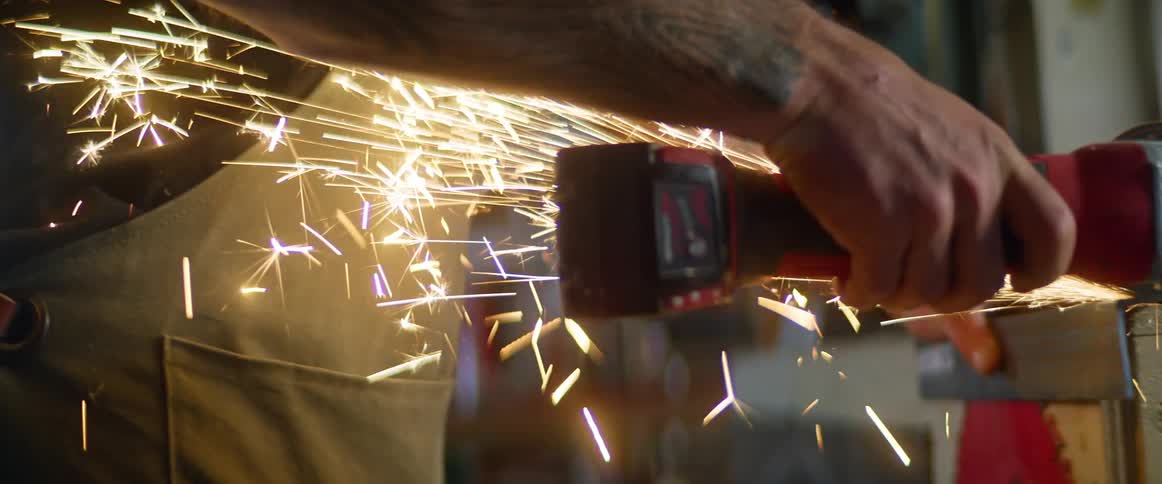 A man grinding metal at a workbench