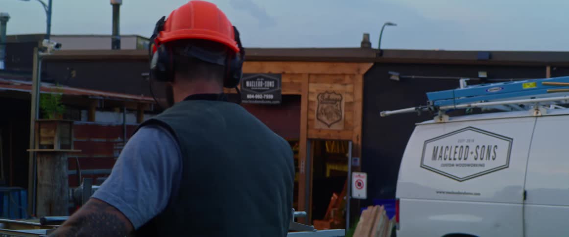 A man in a brightly colored hard hat carries some equipment before he sets it up